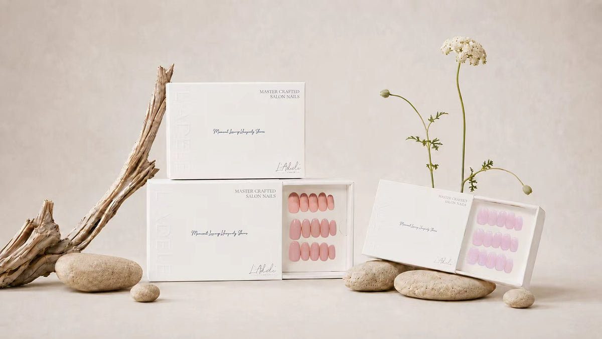 Drei Schachteln handgefertigte Press-on Nails von L'Adele in Rosa und Lila, mit Treibholz und einer Blüte