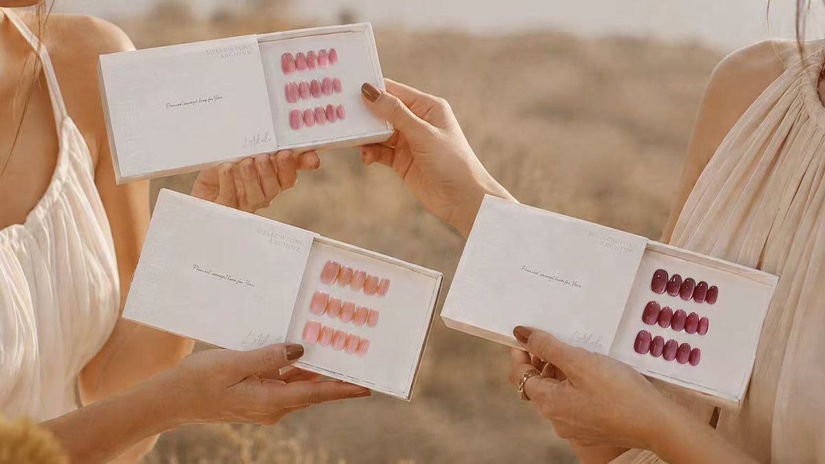 Zwei Frauen halten drei Schachteln handgefertigte Press-on Nails von L'Adele